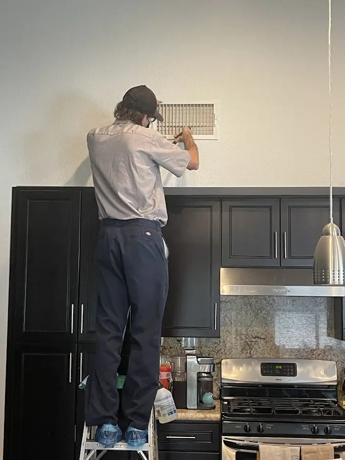 Technician inspecting an air vent during HVAC service in Fort Payne